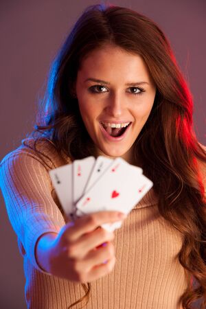 Beautiful brunette holding four aces as a sign for poker game, gambling and casinoの写真素材