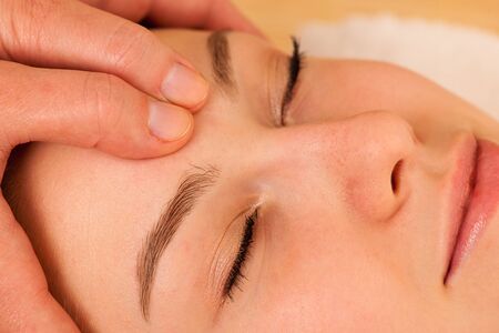 Beautiful blonde woman having a face massage in spa salonの写真素材
