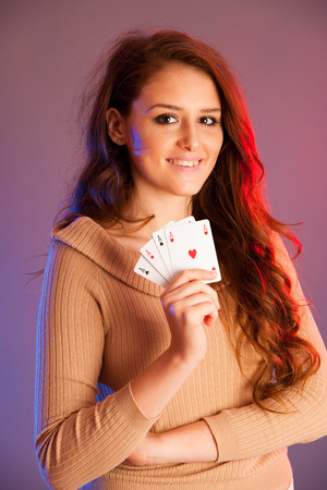 Beautiful brunette holding four aces as a sign for poker game, gambling and casinoの写真素材