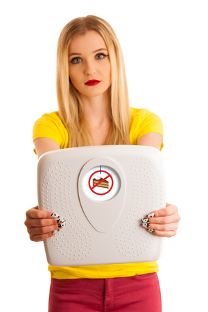 Young woman holding a scale as gesture for weight loose isolated over white backgrondの写真素材