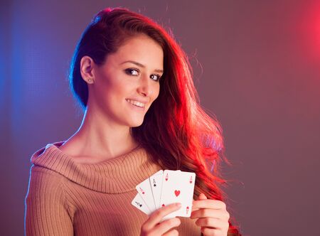 Beautiful brunette holding four aces as a sign for poker game, gambling and casinoの写真素材