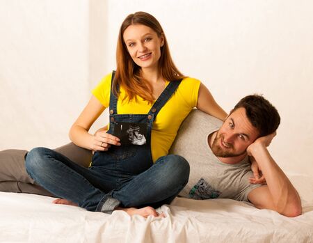 happy couple man and beautiful pregnant woman show with ultrasound baby on white background