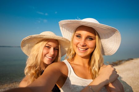 Two young women friends taking selfie on beachの写真素材
