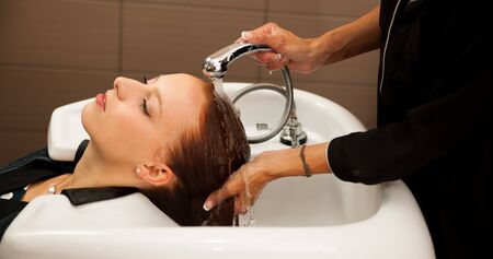 Hair stylist at work - hairdresser washing hair to the customer before doing hairstyle