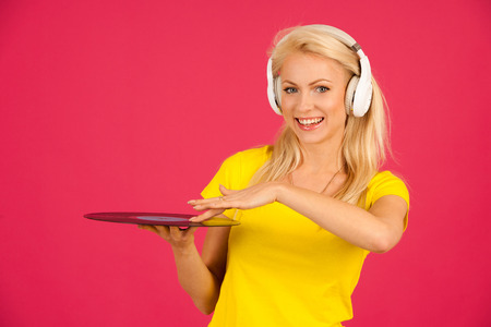 Beautiful young blond woman listening music over vibrant color backgroundの写真素材