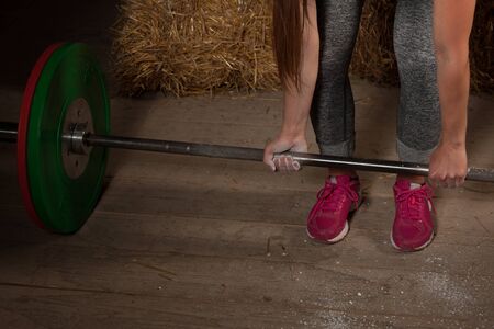 active Woman athlete working out with barbell - powerlifting