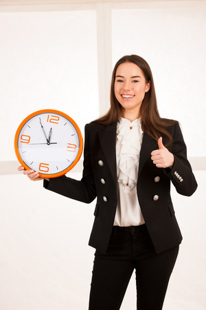 cute woman holding a clock as a symbol of time managementの写真素材