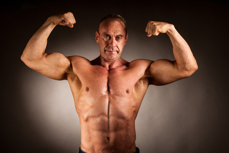 bodybuilder pose in studio over dark backgroundの写真素材