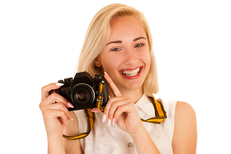 Active young woman taking photos with retro camera isolated over white backgroundの写真素材