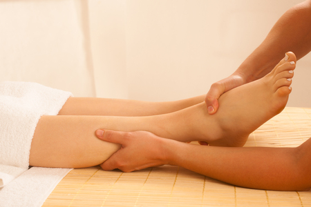 Close-up of female hands doing foot massageの写真素材