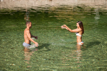Active young couple plays in shallow water on a hot summer morningの写真素材