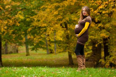 Beautiful pregnant woman outdoor in park on autumn afternoon with vibrant nature colors in background .の写真素材