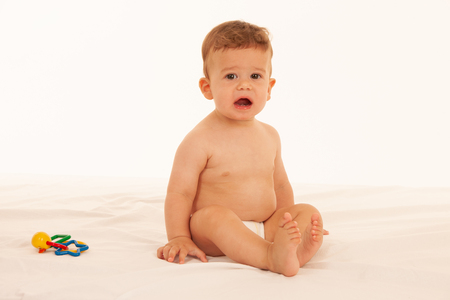 Hapy baby boy in playing on bed isolated over whiteの写真素材