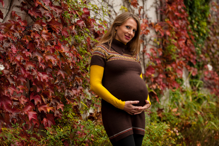 Beautiful pregnant woman outdoor in park on autumn afternoon with vibrant nature colors in background .の写真素材