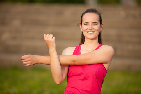 Woman stretch arms on athletic track .の写真素材