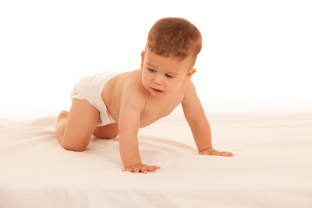 Hapy baby boy in playing on bed isolated over whiteの写真素材