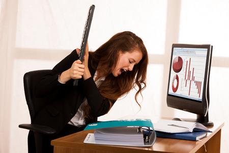 Angry business woman expressing rage at her desk in the officeの写真素材