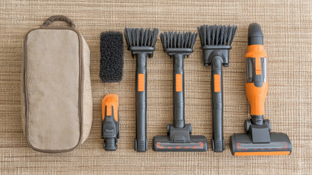 Cordless vacuum kit with multiple heads laid on a beige mat beside storage bagの素材