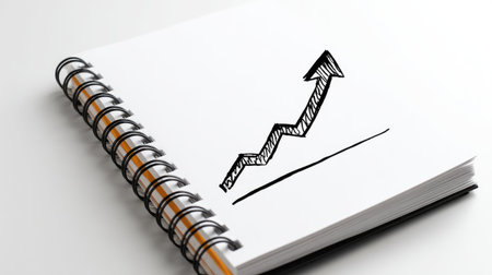 Spiral notebook with hand-drawn arrow rising from base level to peak growthの素材