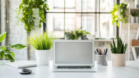 Modern office background with clean white desks, laptops, and potted plants under natural lightingの素材