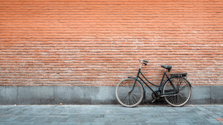 A vintage bicycle leans against a textured orange brick wall in an urban setting, creating a nostalgic and artistic composition for creative projects.の素材