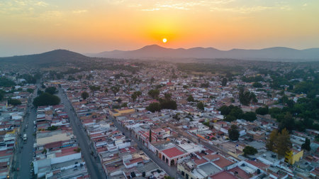 A breathtaking aerial view captures a vibrant city at sunset, framed by distant mountains and a colorful urban landscape. Perfect for travel and nature themes.の素材