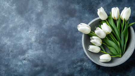 A stylish arrangement of white tulips in a modern bowl on a textured background. This elegant floral display adds a touch of freshness and beauty to any space.の素材