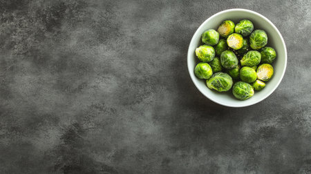 A white bowl filled with fresh Brussels sprouts on a dark textured surface, showcasing a healthy and vibrant ingredient perfect for cooking.の素材