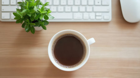 A top view of a cup of coffee beside a small plant on a wooden desk, highlighting a serene workspace with a keyboard in the background, ideal for relaxation and productivity.の素材