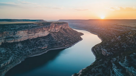 Witness a breathtaking sunrise illuminating a tranquil river valley. The rugged cliffs and calm waters create a stunning natural landscape perfect for adventure and exploration.の素材