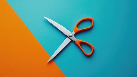 A pair of bright orange-handled scissors placed on a vibrant blue and orange background, ideal for creative projects, crafts, and artistic inspiration.の素材