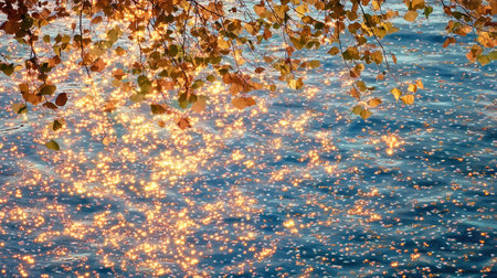A serene view of a water surface shimmering with golden reflections from autumn leaves. The peaceful combination of colors creates a tranquil atmosphere ideal for nature lovers.の素材