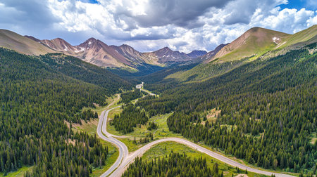 This stunning aerial view showcases a lush green valley, winding roads, and majestic mountains under a beautiful sky filled with clouds, perfect for nature lovers.の素材