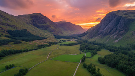 A stunning aerial view of a vibrant sunset illuminating a lush green valley surrounded by majestic mountains, ideal for nature lovers and photography enthusiasts.の素材