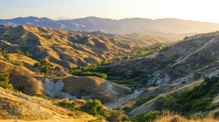 Experience a captivating sunset over undulating hills and lush valleys. The warm lighting highlights the serene beauty of nature in this tranquil landscape.の素材