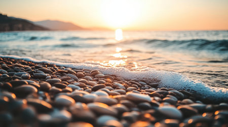 A tranquil sunset scene featuring smooth pebbles along the shore and gentle waves lapping at the beach, creating a serene ambiance perfect for relaxation.の素材