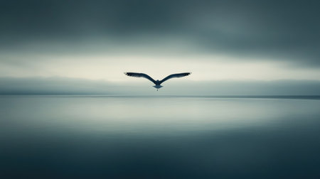 A solitary bird soars gracefully over still water, reflecting the soft colors of a cloudy sky. This serene moment captures nature's beauty and tranquility.の素材