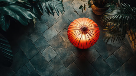 A striking red umbrella rests elegantly on a stone floor, surrounded by lush green plants. This serene composition captures a perfect blend of nature and design, ideal for relaxation.の素材