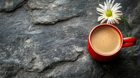 A vibrant red cup of coffee sits on a textured gray stone surface, complemented by a delicate white flower, creating a serene and inviting atmosphere ideal for relaxation and enjoyment.の素材