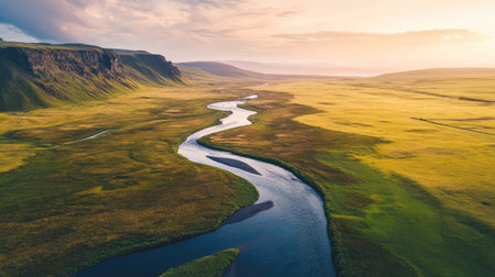 A breathtaking view of a serene river meandering through a lush green valley at sunset. The vibrant landscape showcases the beauty of nature and tranquility.の素材