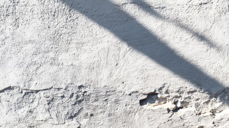 A close-up view of a textured white wall featuring dramatic shadows that emphasize the roughness of the surface, perfect for artistic and architectural compositions.の素材