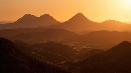 A breathtaking view capturing the serene beauty of a sunrise over majestic mountain peaks, showcasing a layered landscape with soft shadows and golden hues.の素材