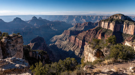 Experience the breathtaking beauty of the Grand Canyon landscape showcasing stunning rock formations, vast terrain, and expansive views under a clear blue sky.の素材