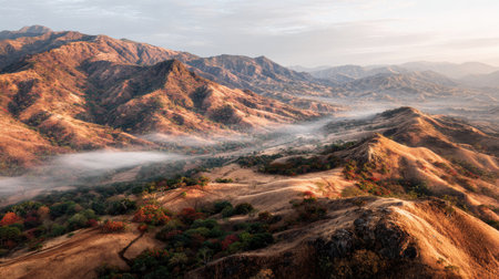 Experience a serene landscape of rolling hills and majestic mountains at sunrise, with mist shrouding the valley, evoking tranquility and natural beauty.の素材