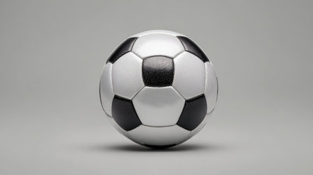 A classic black and white soccer ball displayed against a soft gray background, perfect for illustrating sports themes, recreation activities, and athletic pursuits.の素材