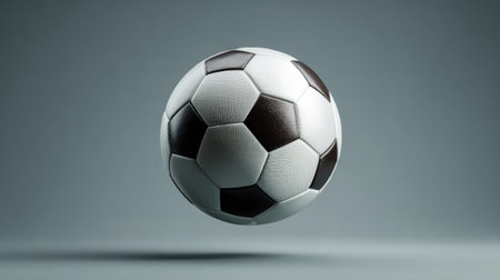 A pristine soccer ball floats in mid-air, set against a smooth gradient backdrop. Perfect for images depicting sports energy, competition, and athletic prowess.の素材