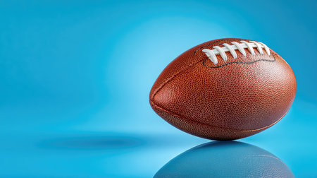 Brown leather American football positioned artistically on a brilliant blue background, showcasing intricate details and texture, perfect for sports-related projects.の素材
