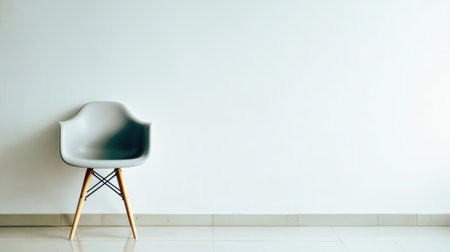 A single gray chair is positioned against a minimalist white wall, embodying modern decor and spacious living. Ideal for concepts of elegance and simplicity.の素材