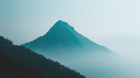 A stunning view of a solitary mountain peak enveloped in mist and fog. The serene landscape embodies tranquility, making it perfect for nature enthusiasts and wanderers.の素材