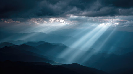 Captivating mountain landscape featuring dramatic rays of light piercing through thick clouds at dusk, creating a serene and mystical atmosphere in nature.の素材